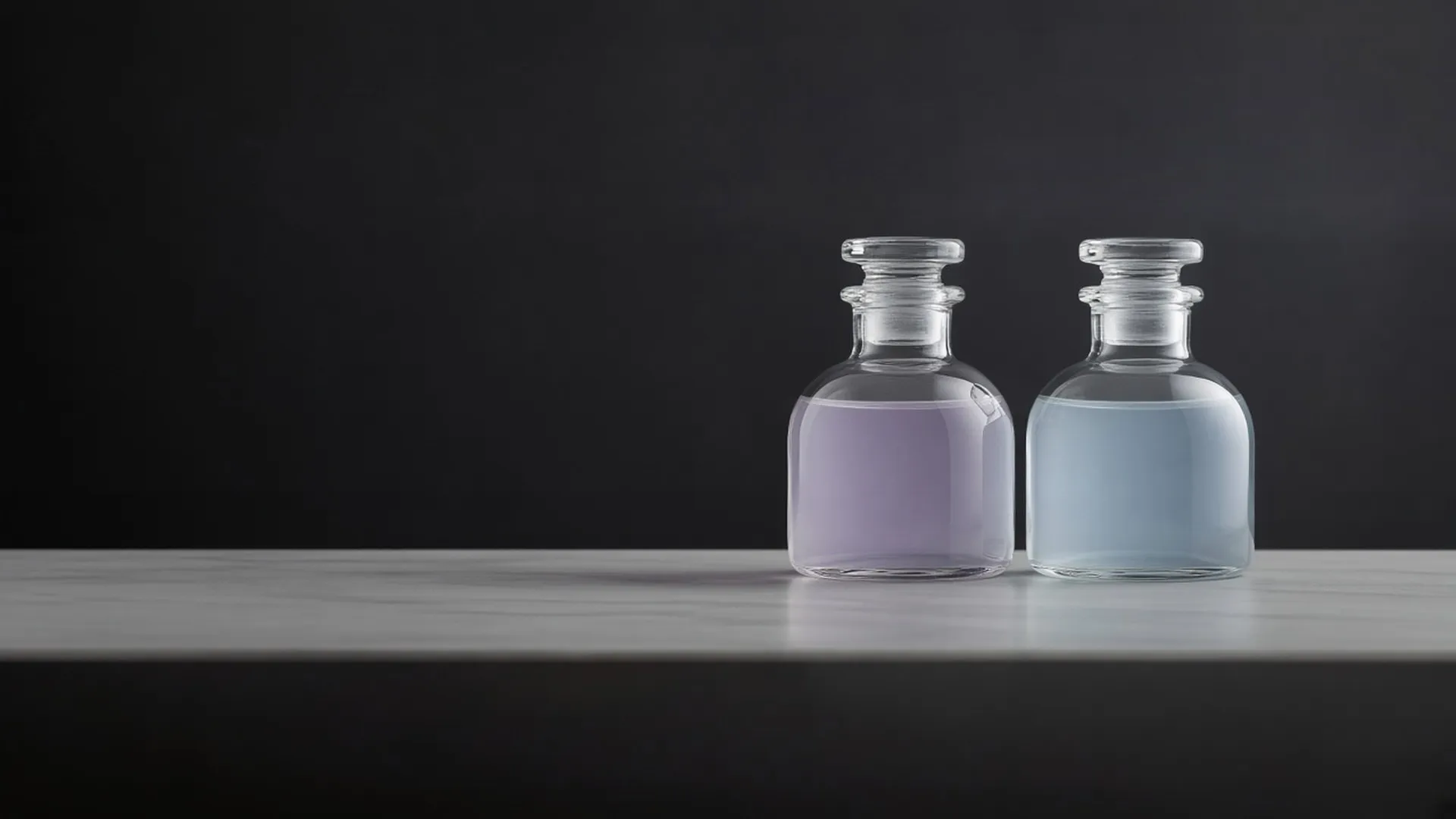 Two identical clear unlabeled glass bottles side by side, one pale lilac and one pale blue